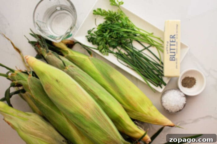 Perfect Slow Cooker Corn on the Cob 3 An arrangement for Crockpot Corn on the Cob: fresh corn on the cob, a glass of water, a bunch of parsley and chives on a white plate, unsalted butter, and small bowls of salt and pepper on a pristine white surface.
