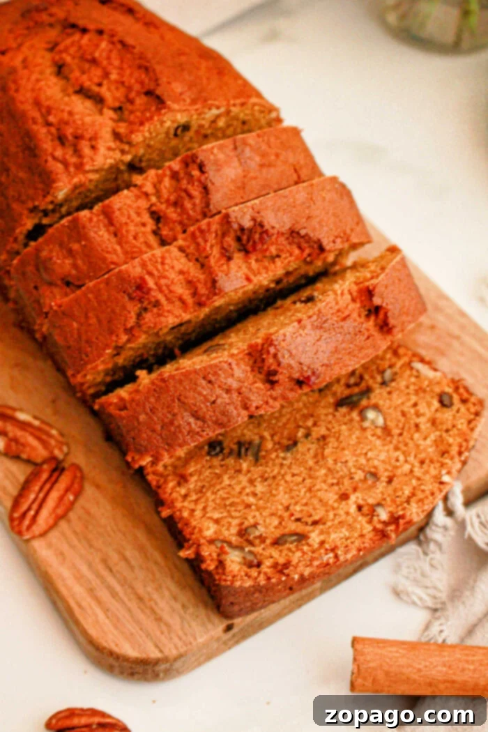 Spiced Sweet Potato Loaf 2 A sliced loaf of banana nut bread sits on a wooden cutting board, with some pecan halves scattered around. The bread has a golden-brown crust and visible pecan pieces in each slice, reminiscent of Sweet Potato Bread with Cake Mix.