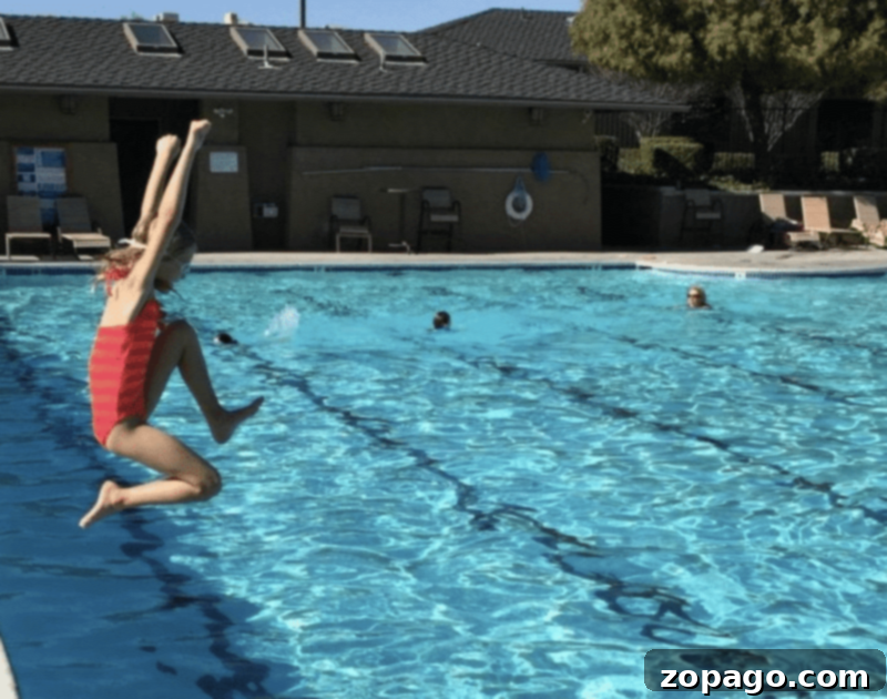 Summer Fun on a Budget for Kids 3 Two children happily sliding down a large inflatable backyard water slide with a soft landing ramp, enjoying summer fun