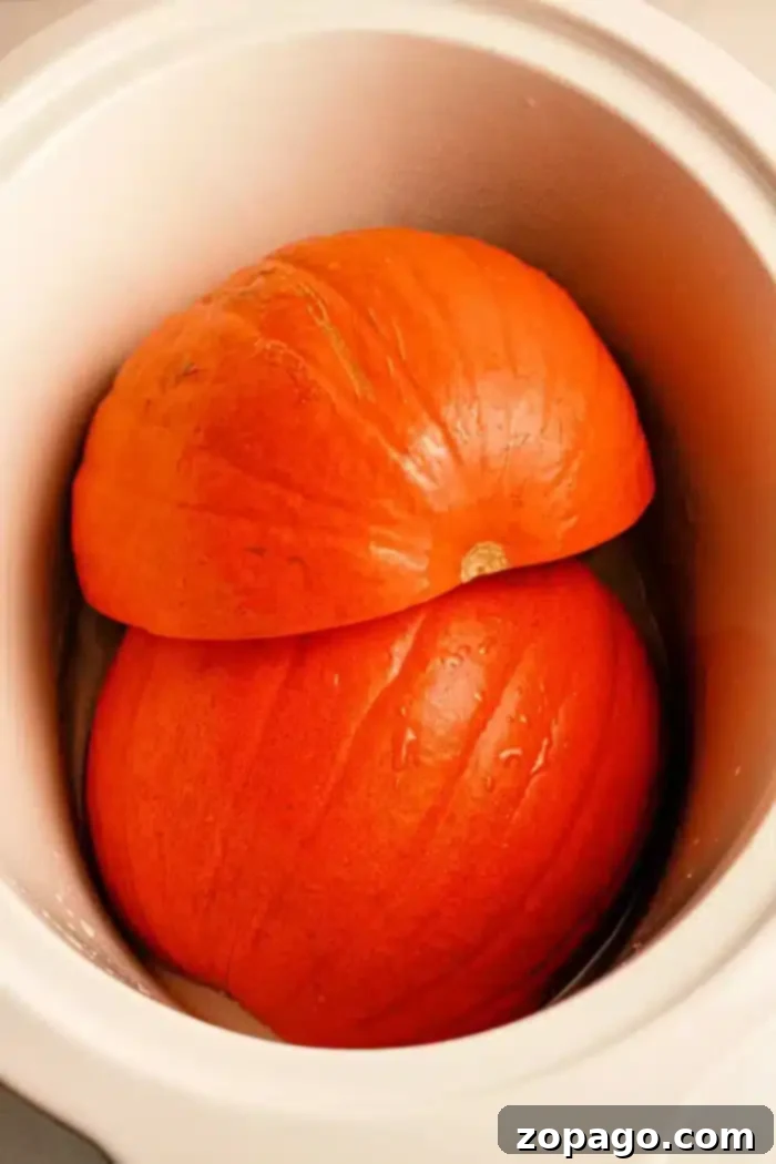 Crockpot Pumpkin Bliss 2 Two large, bright orange pumpkin halves, carefully prepared and placed snugly inside a pristine white slow cooker, hinting at the ease of the upcoming cooking process.