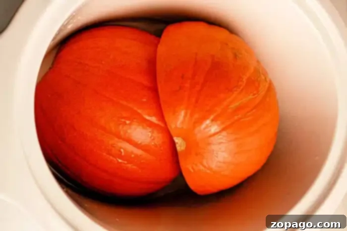 Crockpot Pumpkin Bliss 5 A Pumpkin in a Slow Cooker, cut in half with the two halves placed next to each other. The bright orange flesh of the pumpkin is visible, and there is slight moisture on the surface.