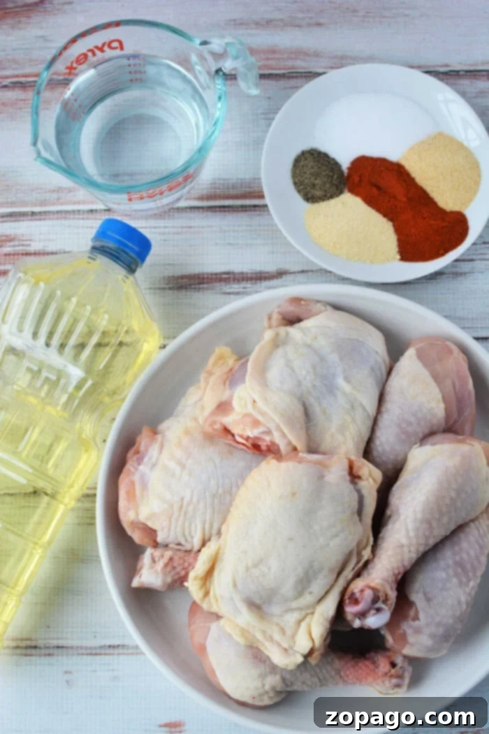 Crispy Pressure Cooker Fried Chicken 3 A raw chicken awaits transformation beside an oil bottle and a measuring cup of water, with a plate of spices ready to spice things up. Perfect ingredients for pressure cooker magic or crispy fried chicken bliss, all resting on a light wood surface.