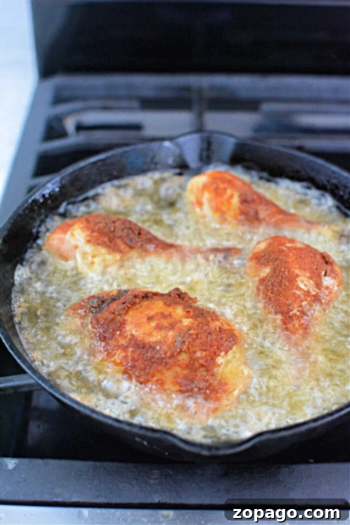 Speedy Pressure Fried Chicken 5 Four pieces of breaded chicken sizzling in a pan, reminiscent of pressure cooker fried chicken, frying to golden perfection with oil on a stovetop.