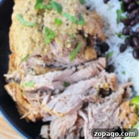 Savor shredded pork with herbs, paired perfectly with white rice and black beans, all garnished with lime wedges on a black plate—an exquisite roast recipe for any culinary enthusiast.
