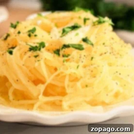 Effortless Slow Cooker Spaghetti Squash 7 A slow cooker spaghetti squash sits on the plate, enhanced by a parsley garnish and a sprinkle of black pepper.
