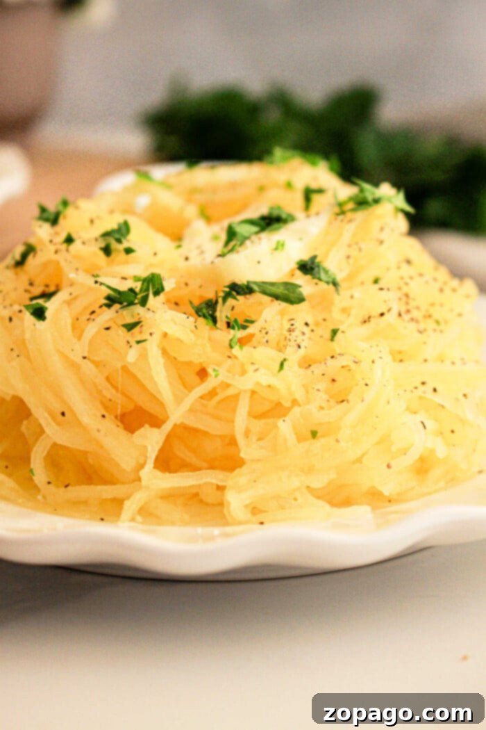 Effortless Slow Cooker Spaghetti Squash 8 A slow cooker spaghetti squash sits on the plate, enhanced by a parsley garnish and a sprinkle of black pepper.