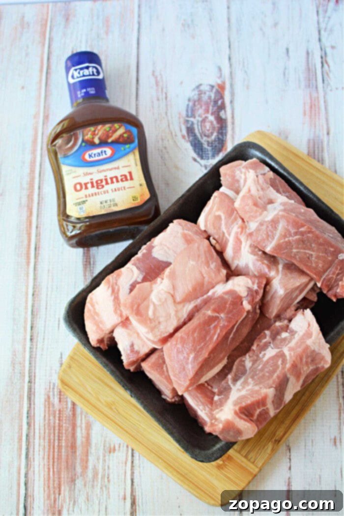 Baked Boneless Pork Ribs 3 Raw boneless pork ribs rest on a black tray beside a bottle of Kraft Original Barbecue Sauce, perfect for your next pork ribs recipe, all set on a wooden surface.