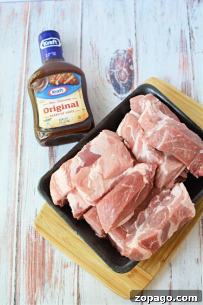 Raw boneless pork ribs rest on a black tray beside a bottle of Kraft Original Barbecue Sauce, perfect for your next pork ribs recipe, all set on a wooden surface.