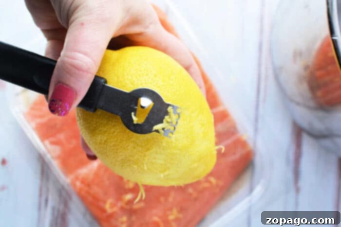Quick Pressure Cooker Salmon 4 A hand expertly uses a zester to zest a lemon over a fresh container of salmon, ready to be transformed into a delightful dish. Consider using your pressure cooker for perfectly tender and flavorful results in no time.