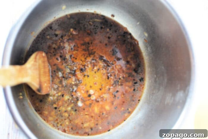 Perfect Pork Steaks 4 A pressure cooker pot with a wooden spoon, filled with simmering dark brown sauce and seasonings, preparing a delicious pork steak recipe.