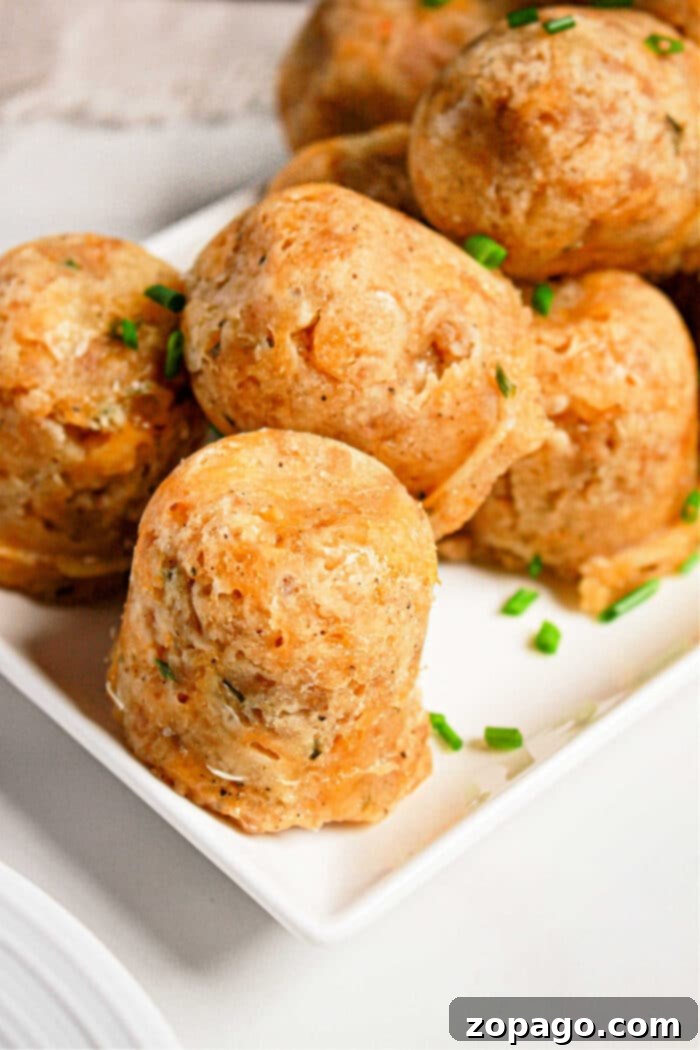 Easy Instant Pot Sausage Balls 2 Round sausage balls made in a pressure cooker, are garnished with chopped chives on a white square plate.