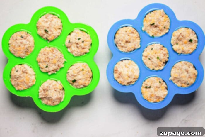 Easy Instant Pot Sausage Balls 5 Two silicone molds filled with uncooked sausage balls, one green and one blue, sit on a light gray surface, ready to become delicious pressure cooker creations.