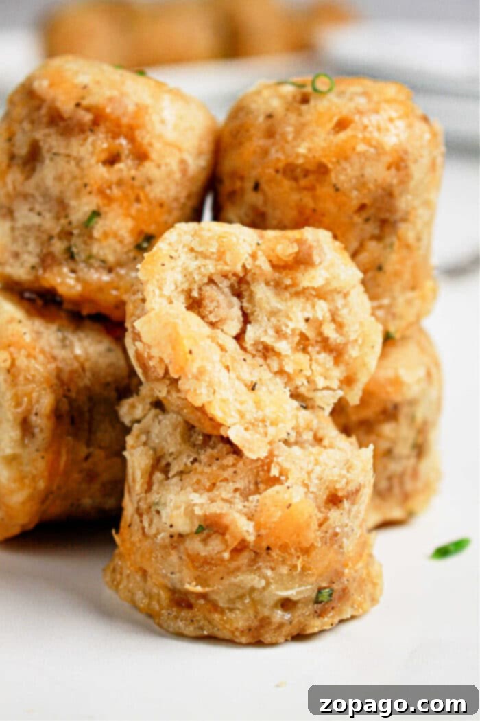 Easy Instant Pot Sausage Balls 6 Close-up of stacked, golden-brown savory muffins with a cracked one on top, revealing a soft, textured interior—an inviting sight reminiscent of warm sausage balls fresh from the pressure cooker.