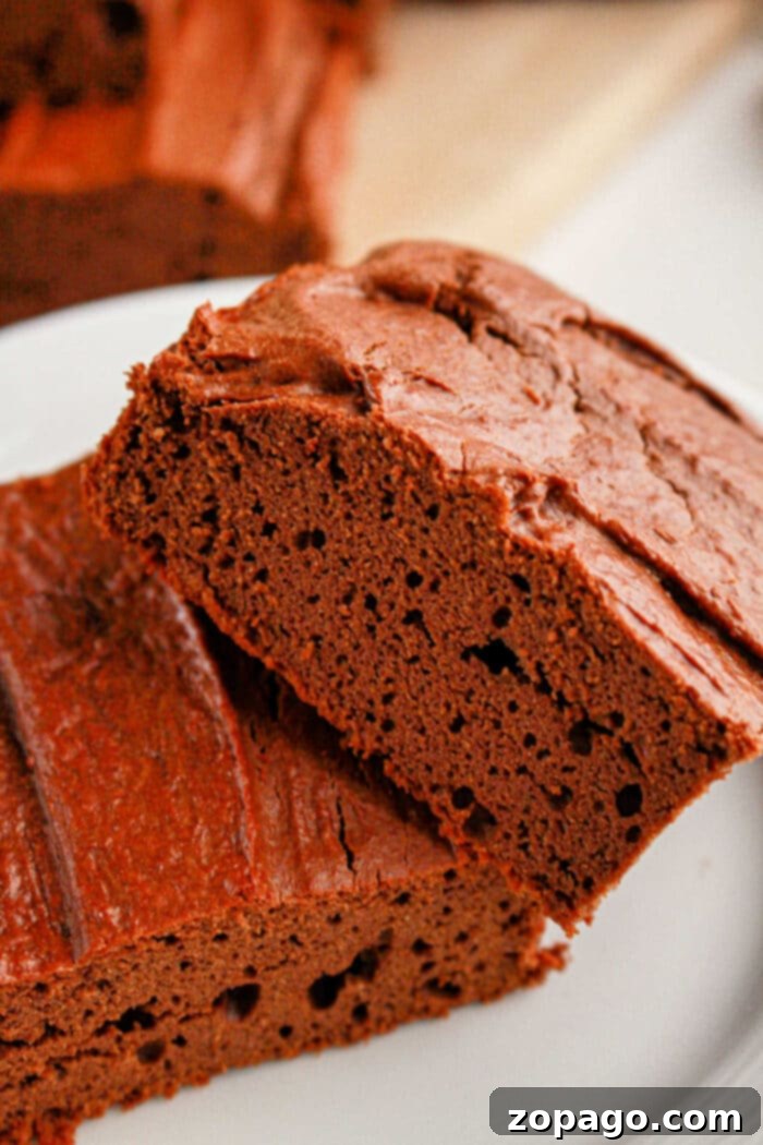High-Protein Brownie Bites 6 Close-up of two decadent slices of protein brownies on a white plate, showcasing their rich, fudgy texture and appealing appearance.