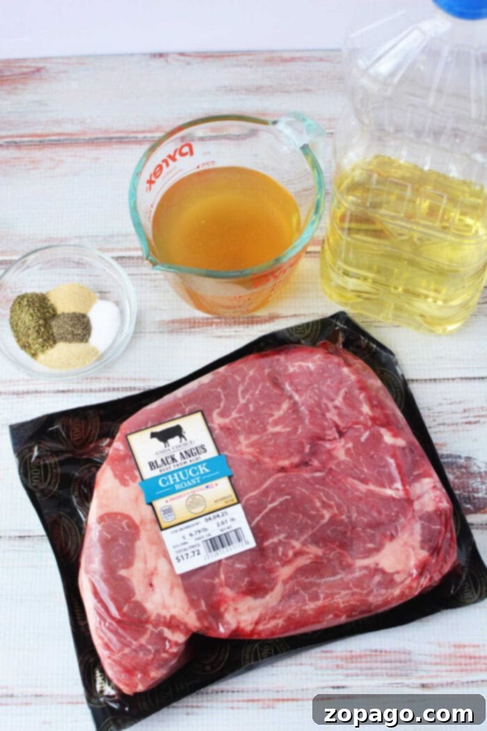 Melt-in-Your-Mouth Boneless Chuck Roast 3 Ingredients for boneless chuck roast on a table: a raw boneless chuck roast, a bottle of oil, beef broth in a measuring cup, and a glass bowl of mixed spices.