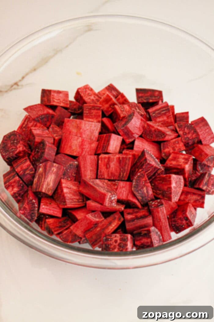 Vibrant Purple Sweet Potato Creations 4 A glass bowl filled with cubed pieces of fresh purple yam, perfect for your next purple sweet potato recipe, rests on a white surface.