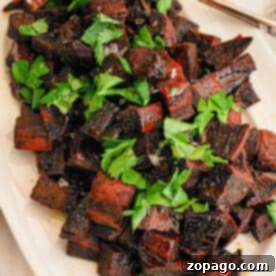 Vibrant Purple Sweet Potato Creations 7 Cubed vibrant purple sweet potatoes sit elegantly on a white plate, complemented by a handy spoon.