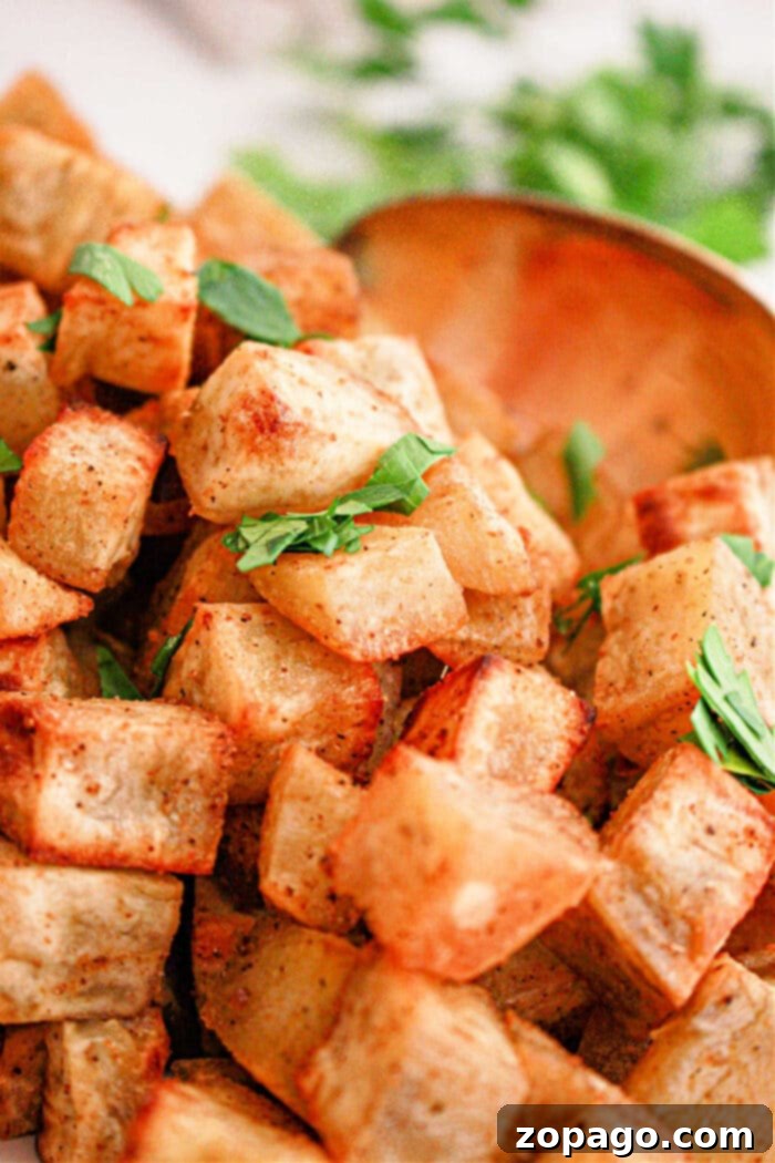 Creamy White Sweet Potato Delight 6 Crispy roasted white sweet potato cubes garnished with fresh parsley, with a wooden spoon in the background—a delicious white sweet potato recipe.