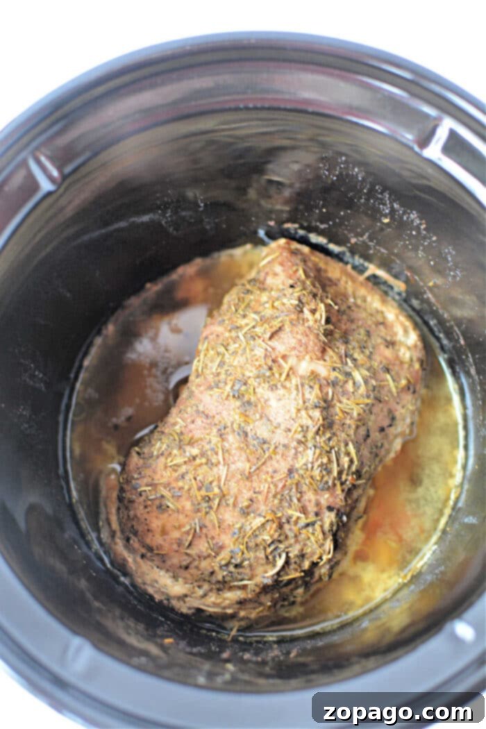 Tender Slow Cooker Porketta 5 A seasoned Porketta Roast is cooking slowly, melding flavors with its rich, savory juices.