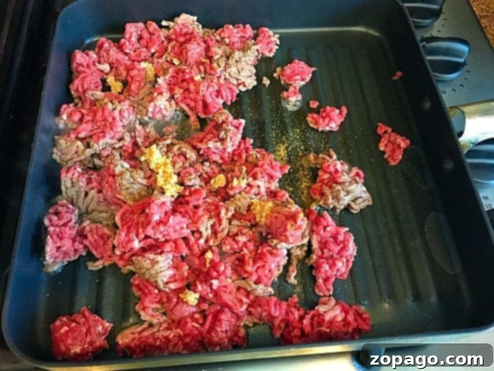DIY Crispy Taco Bowls 4 Ground beef with spices sizzles in a grill pan on the stovetop, perfect for a flavorful taco salad bowl filling.