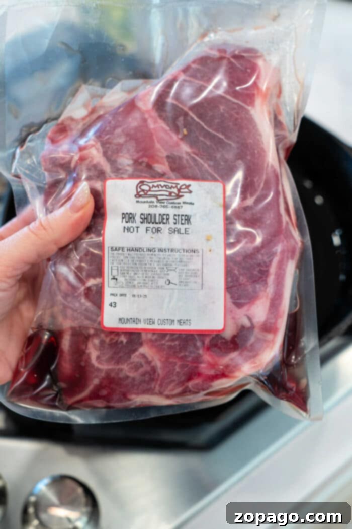 Pork Blade Steak 3 A hand holds a vacuum-sealed package of Pork Shoulder Steak labeled Not For Sale.