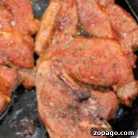 Seared flavorful Pork Shoulder Steak, coated with seasoning and sizzling in a cast iron skillet.