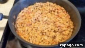 Cooked seasoned ground meat in a black skillet on a stovetop, perfect for adding rich flavor to your favorite crockpot tortellini soup recipe.