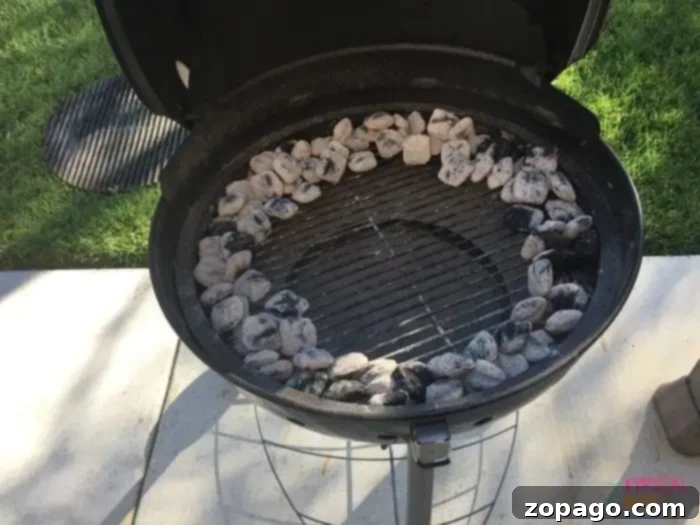 Proper charcoal arrangement for indirect heat: coals on the perimeter, center empty for beer can chicken. #grillingtips #indirectheat A charcoal grill with unlit coals arranged in a circular pattern around the outer edge, leaving the center clear for indirect cooking of beer can chicken.