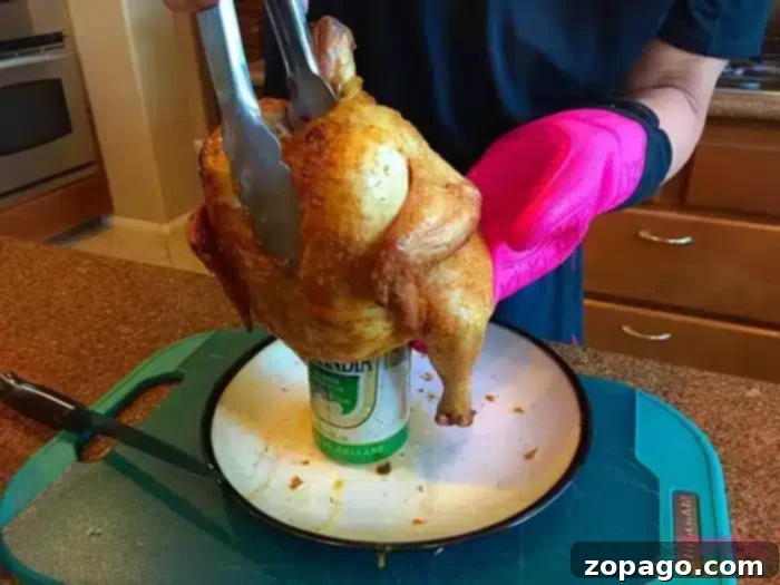 Safely removing the expertly roasted beer can chicken from the charcoal grill, now golden and perfect, ready for a vital resting period before carving. A person wearing a pink oven mitt meticulously uses tongs to lift a perfectly roasted beer can chicken from a charcoal grill. The succulent bird is then carefully placed onto a crisp white plate, situated on a wooden cutting board in the kitchen, awaiting carving.