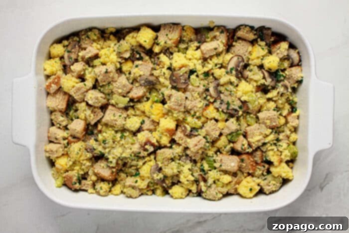 Classic Jiffy Cornbread Dressing 5 A casserole dish filled with Jiffy cornbread stuffing mixed with vegetables and herbs, ready to be baked.