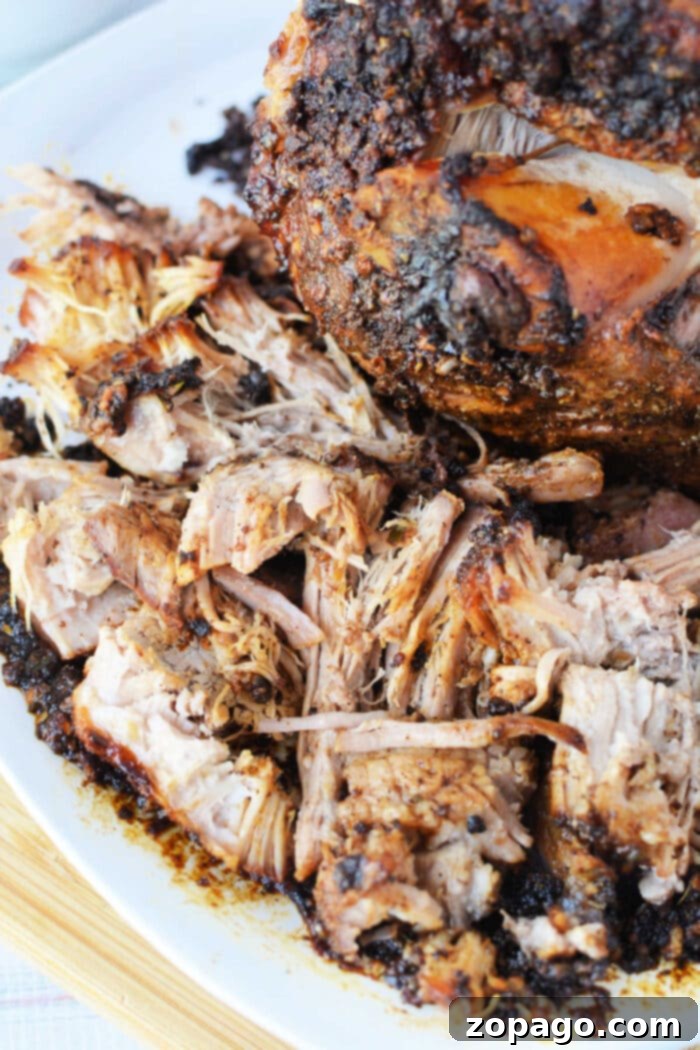 Oven Roasted Pork 2 Shredded, seasoned pork roast with crispy, browned edges on a white plate—an irresistible pork roast recipe made to perfection in the oven.
