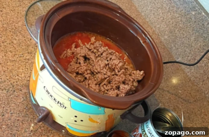 Versatile Slow Cooker Soups: Hearty, Easy, and Healthy Crockpot Meals Ground beef and tomato sauce simmering in a Crock-Pot, reminiscent of slow cooker chili or beef soup recipes, with empty cans scattered on the kitchen countertop, highlighting simple ingredients.