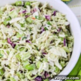 The Perfect Coleslaw for Pulled Pork 4 A bowl of fresh coleslaw, perfect for a pulled pork feast, features crisp cabbage, carrots, and green onions, all served beside sliced lemons.