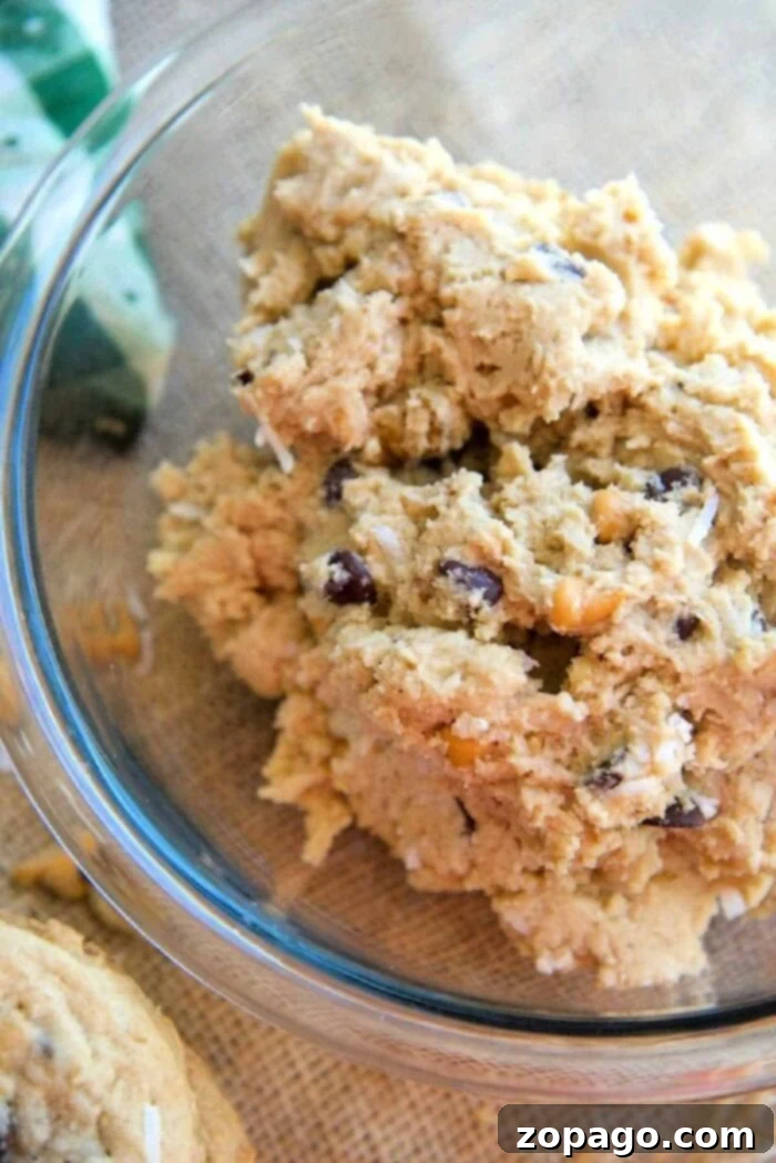 Everything Goes Cookies 4 Deliciously textured cowboy cookies, abundantly loaded with chocolate chunks, chopped nuts, and hearty oats, showcasing their inviting crunch and chew.