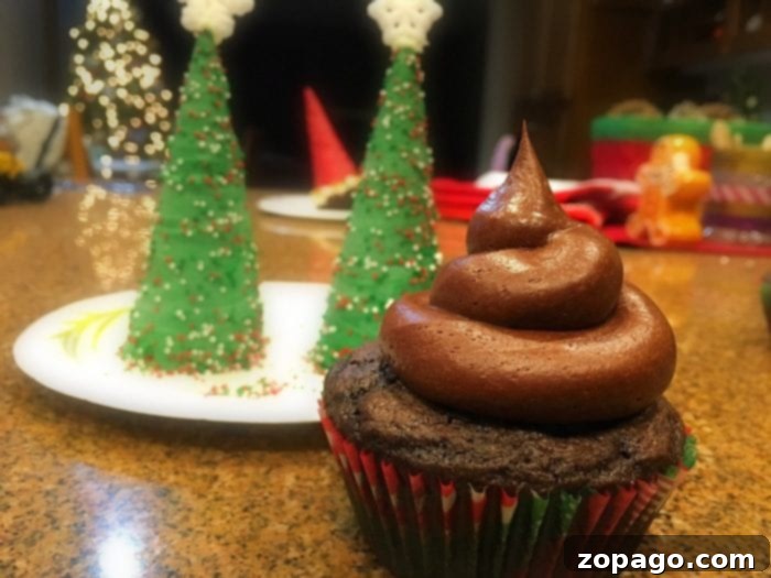 The final touch: adding a sparkling star or snowflake to the top of your Christmas Tree Cupcake. Close-up of a finished Christmas Tree Cupcake with a star topper