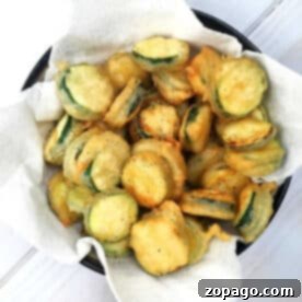 Crispy Baked Zucchini Chips 2 A bowl of crispy salt and pepper zucchini chips rests on a paper towel-lined plate.