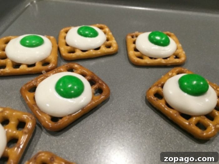 Green Eggs and Ham Delight 2 Close-up of pretzels with white candy melts partially melted on them, ready for green candies.