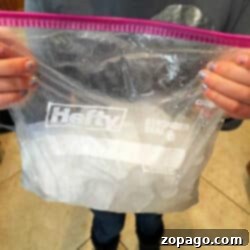 A person holds a clear plastic bag with a Hefty logo, its contents resembling ingredients for how to make ice cream at home, ready to transform into a delightful dessert.