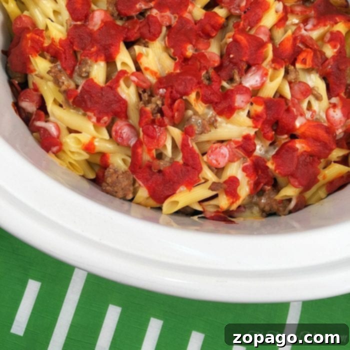 This slow cooker pizza casserole recipe is amazing! So easy to make in your crockpot and great for dinner or a party with kids. #slowcooker #pizza #crockpot #casserole #crockpotrecipes #thetypicalmom Crockpot Pizza Casserole featuring elbow macaroni, rich sauce, and melted cheese