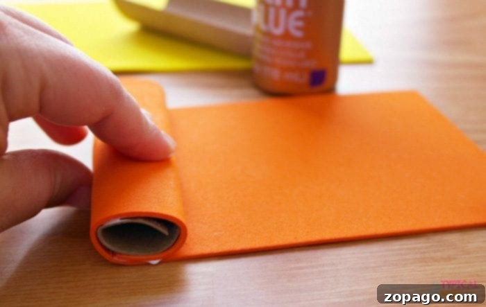 Create Lorax Truffula Tree Finger Puppets 4 Crafting process: Gluing a cut toilet paper roll to form the base of a Dr. Seuss character puppet.