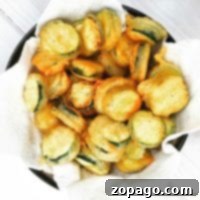 A bowl of crispy salt and pepper zucchini chips rests invitingly on paper towels.
