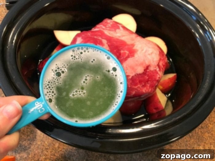 Ultimate Slow Cooker Corned Beef Brisket 6 Pouring beer over corned beef in a slow cooker