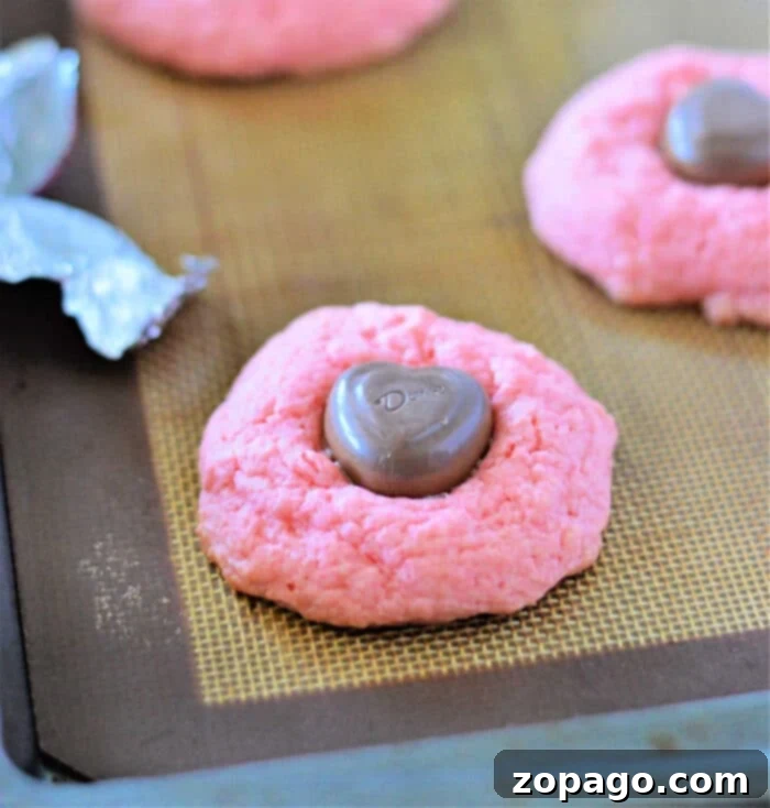 Easy Strawberry Cake Mix Cookies 7 A plate of pink strawberry cookies, some with chocolate hearts, perfect for a festive occasion.