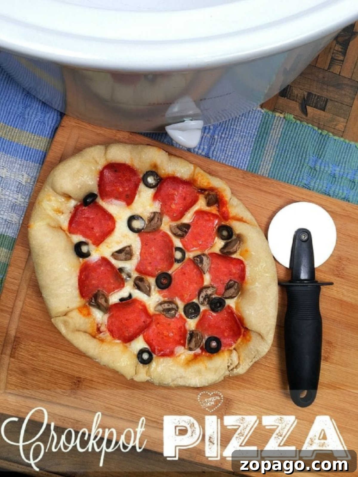 Slow Cooker Pizza 2 A homemade crock pot pizza, richly topped with pepperoni, mushrooms, and black olives, sits on a wooden cutting board beside a pizza cutter and a slow cooker, ready to be served.