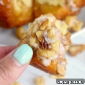 Close-up of a hand holding a walnut pastry piece, suggesting a delicious brunch item.