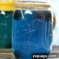 Mason jar filled with a vibrant blue Hawaiian Punch, adorned with a charming twine bow, perfect for a baby shower.