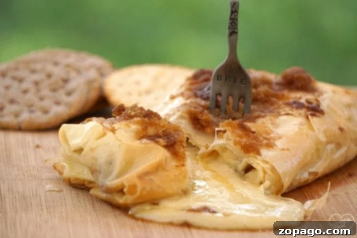 Flaky Baked Brie 5 The best baked brie, golden brown and perfectly melted, served on a wooden board with crackers.