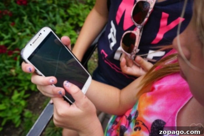 Kids entertained with a device while waiting in line at Disneyland. Kids playing on a device while waiting in line at Disneyland