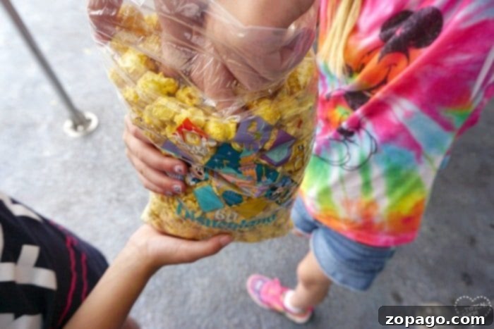 Family sharing a large caramel corn snack at Disneyland to save money. Family sharing a large snack at Disneyland