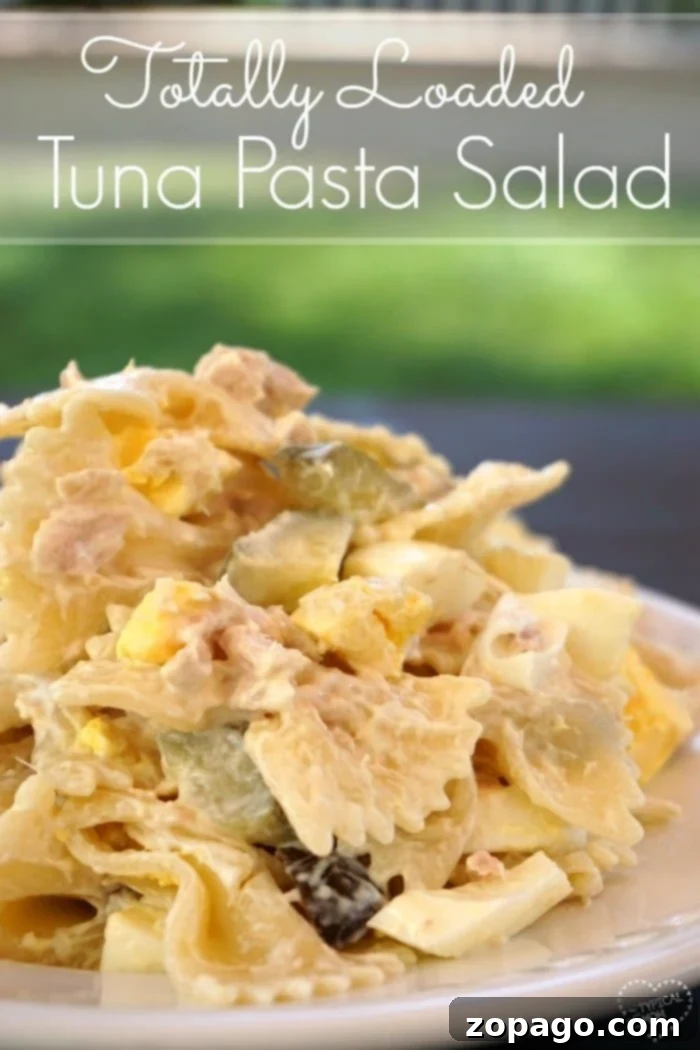 Irresistibly creamy and loaded macaroni tuna salad, perfect for any gathering. Close-up of a generous serving of loaded macaroni tuna salad with bowtie pasta, flaked tuna, diced dill pickles, and chopped hard-boiled eggs, garnished with fresh parsley.